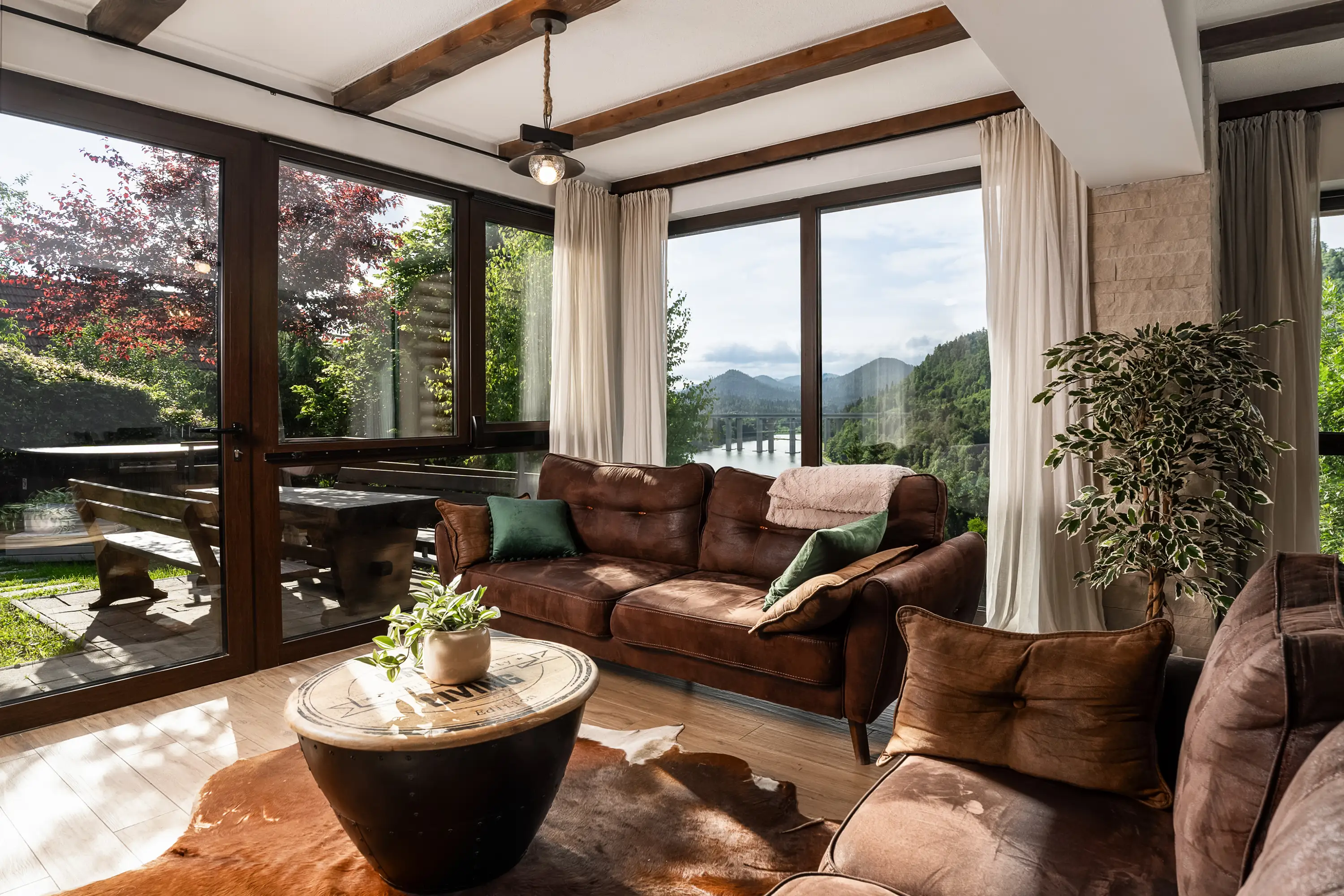 Dnevni boravak otvorenog tlocrta s panoramskim pogledom na jezero i planine kroz staklene zidove od poda do stropa