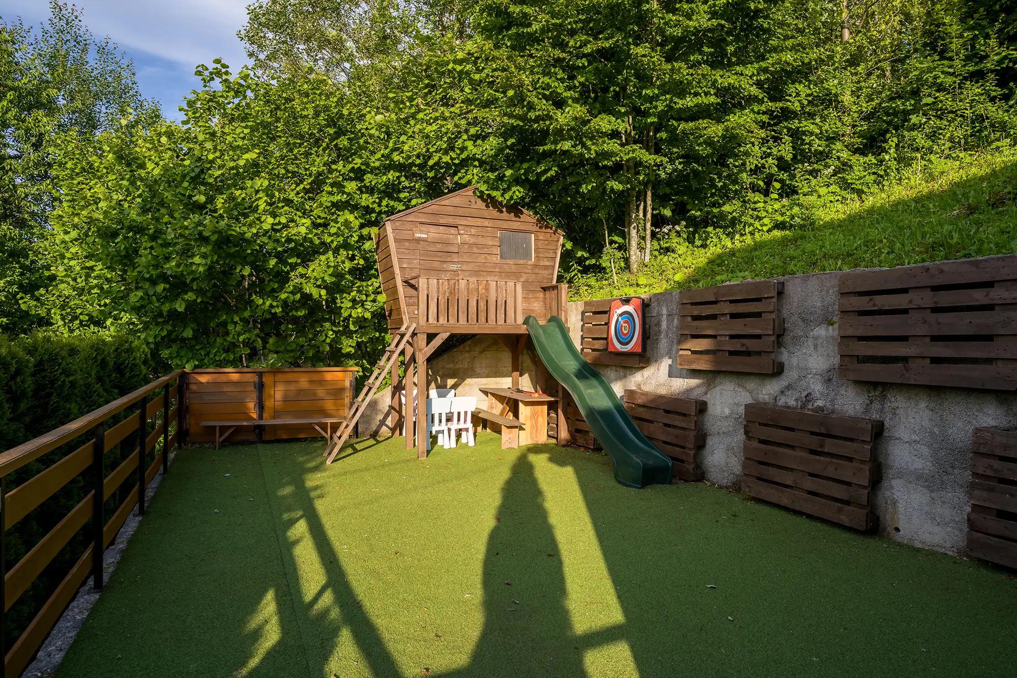 Drveno igralište s kućicom na drvetu, toboganom i metom za pikado u šumi